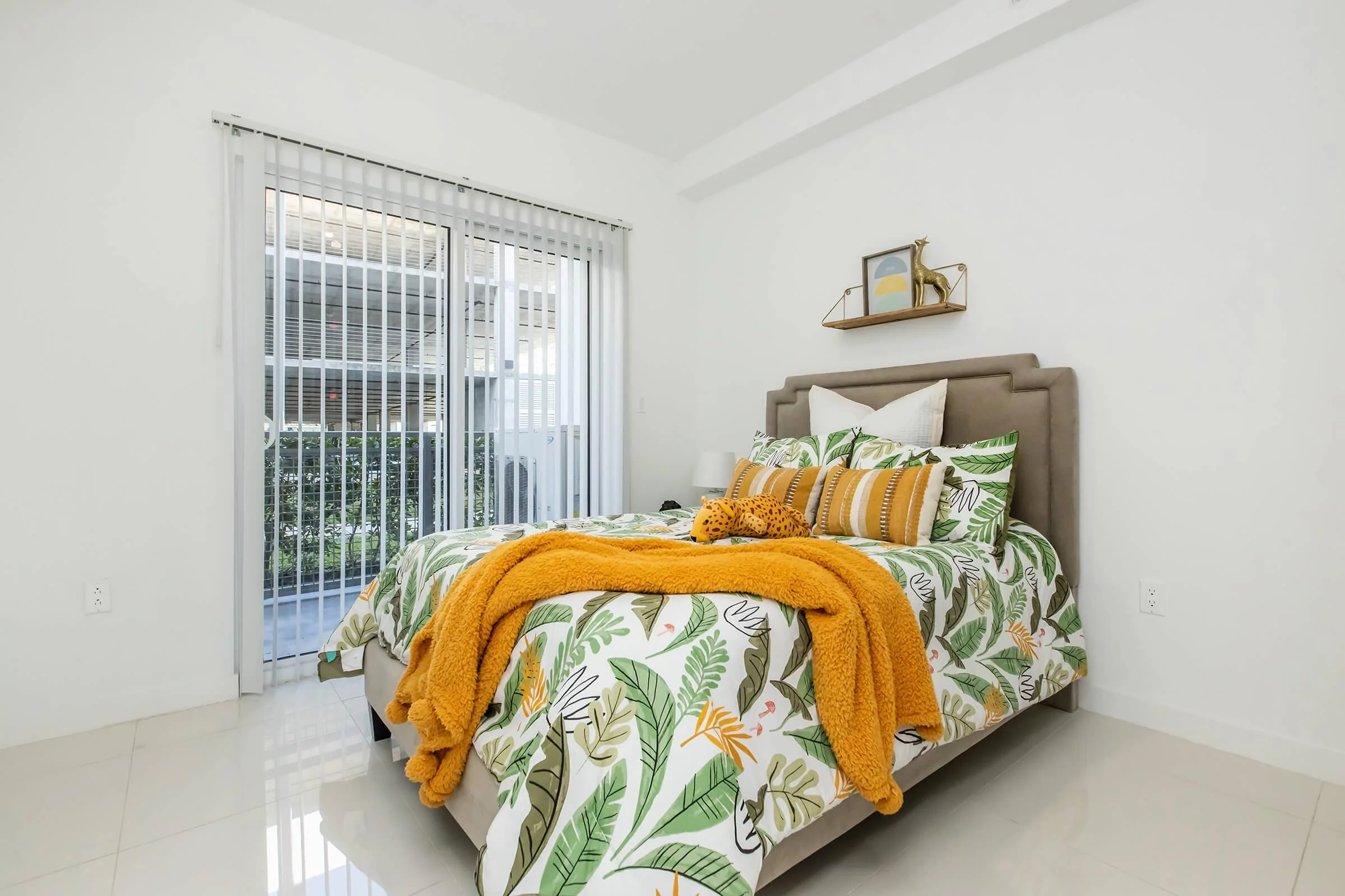 Model D bedroom with tropical bedding and balcony doors.