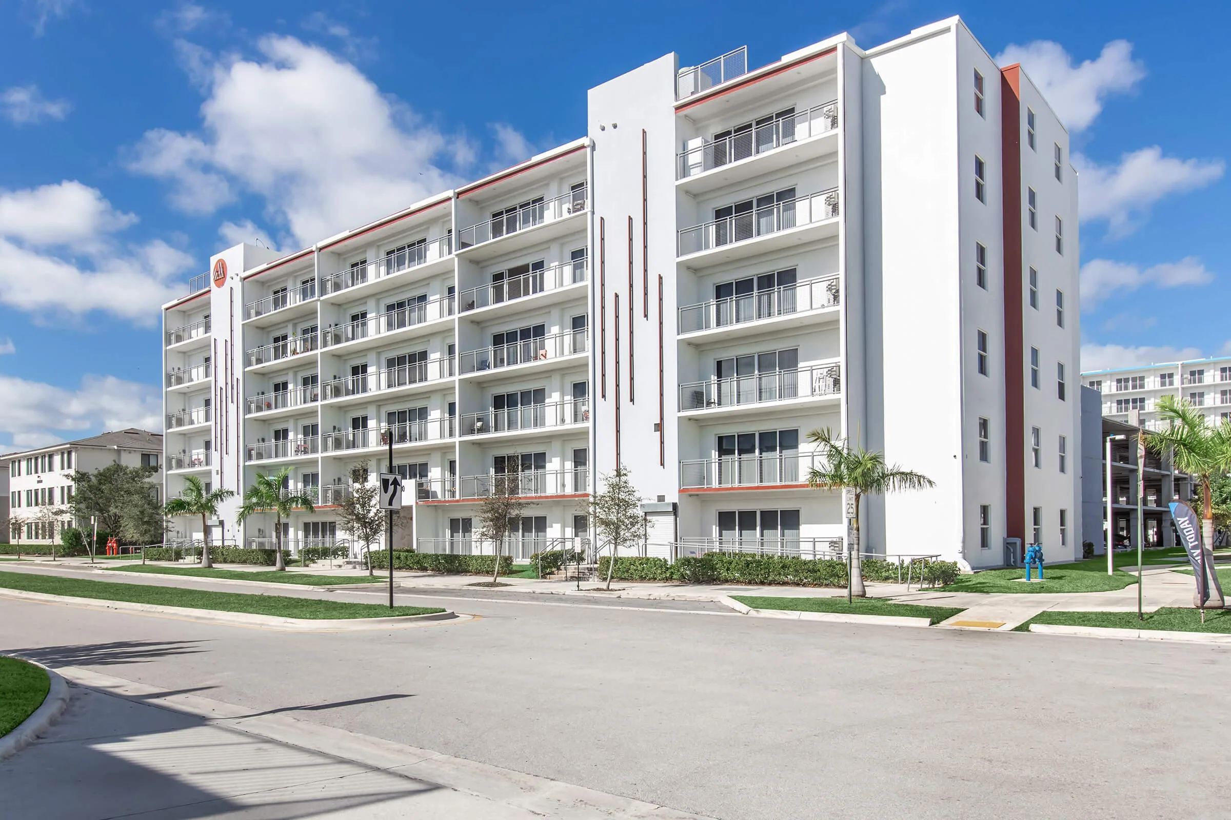 Daytime exterior of Modern Towers with balconies and palm landscaping.